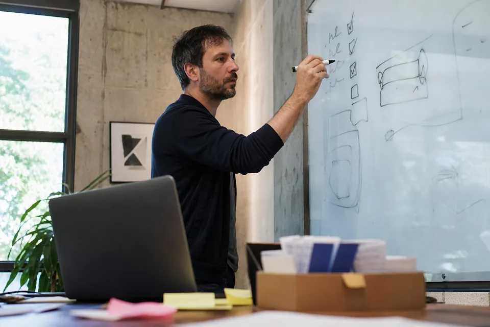 Brand manager at a whiteboard listing social platforms to claim a new brand handle on