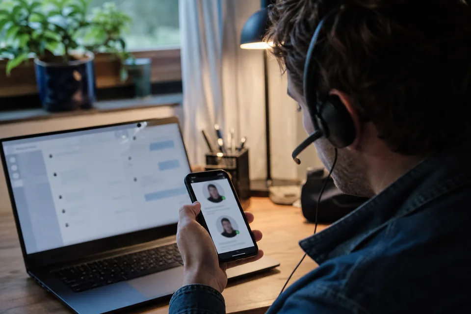 Hands typing on a laptop with a magnifying glass beside it