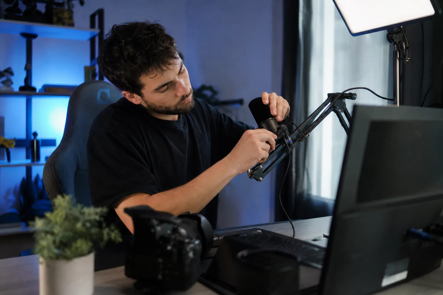Adult streamer adjusting a microphone at a home streaming desk