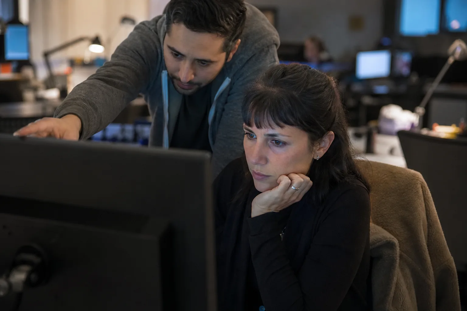Trust and safety specialist talking with a colleague in an open office in natural light